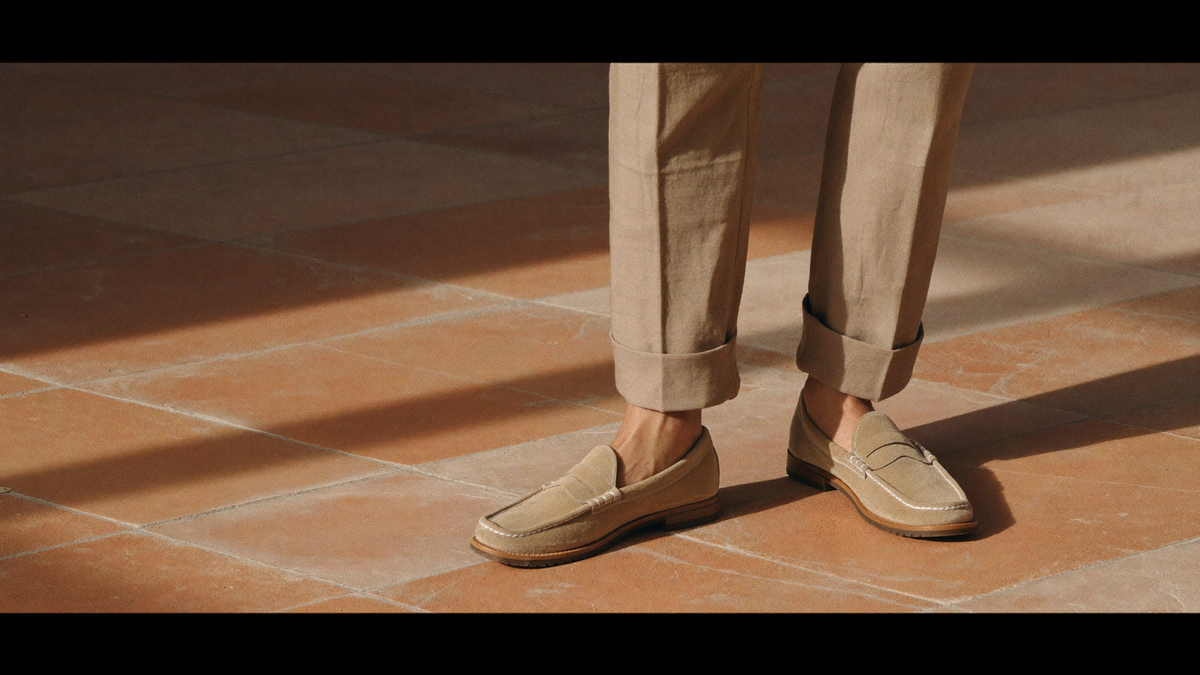 Mocassins en daim beige portés sans chaussettes sur un sol en terre cuite